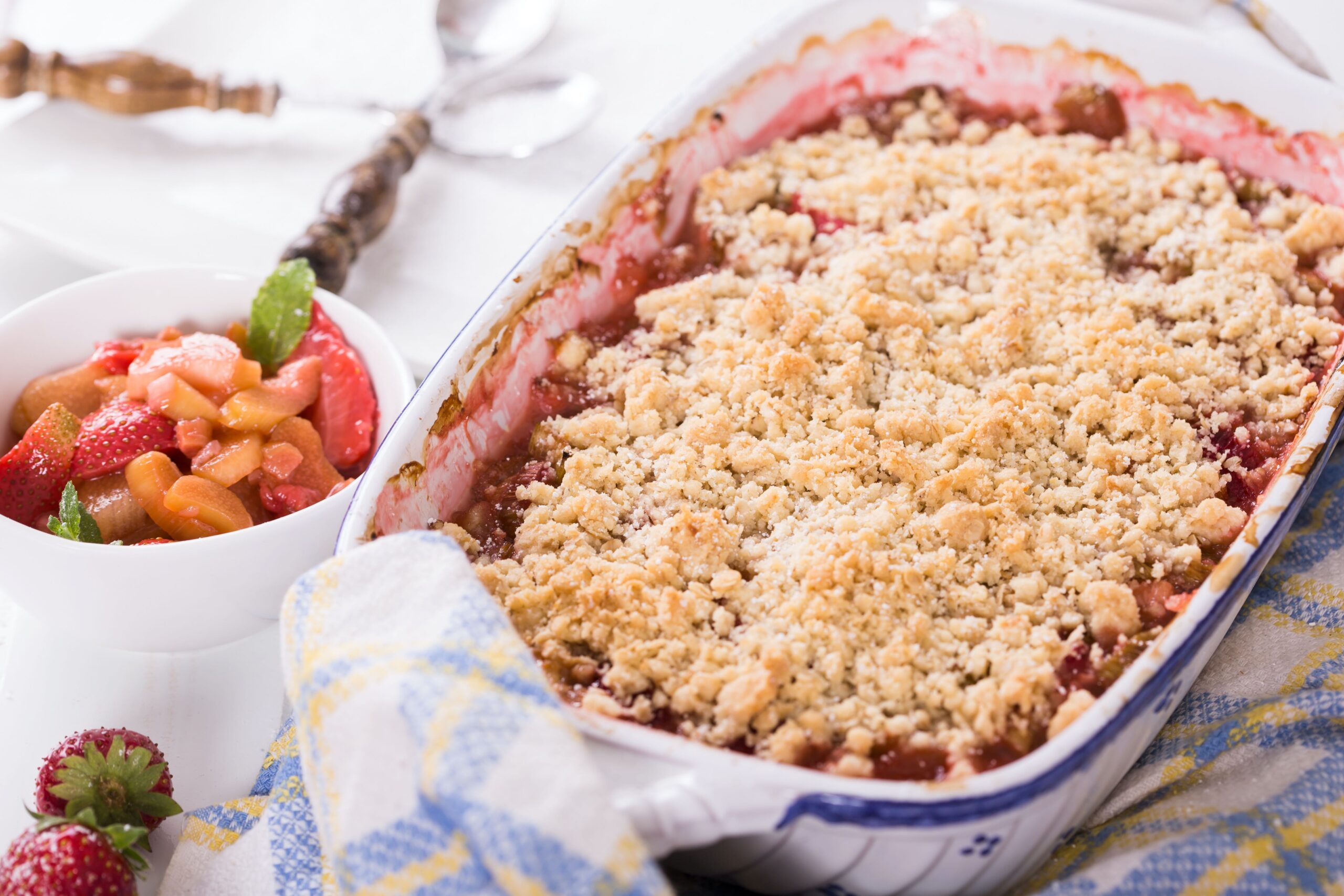 strawberry crisp dessert in a blue and white baking dish with strawberries around it 
