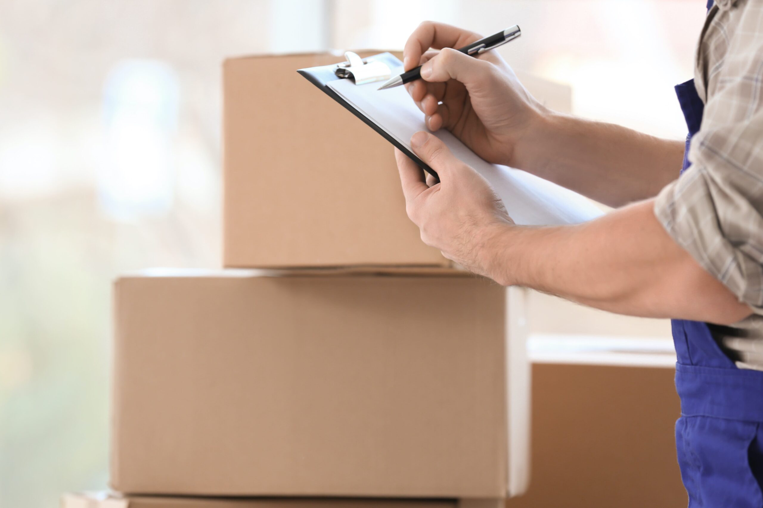 Man holding clipboard on blurred boxes background