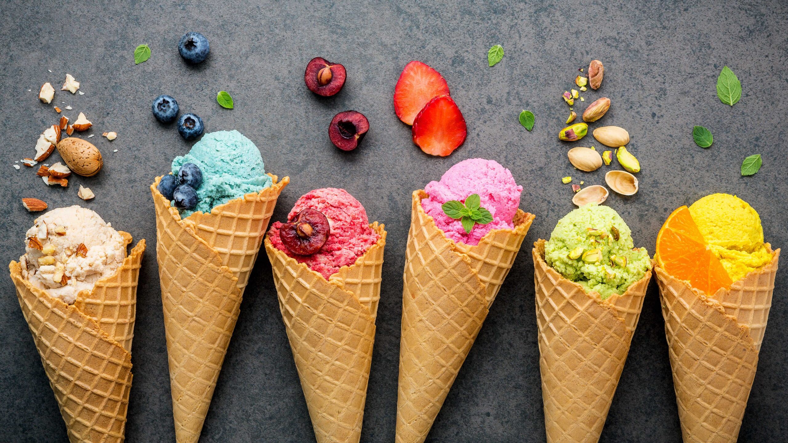 Various of ice cream flavor in cones blueberry ,strawberry ,pistachio ,almond ,orange and cherry setup on dark stone background . Summer and Sweet menu concept.