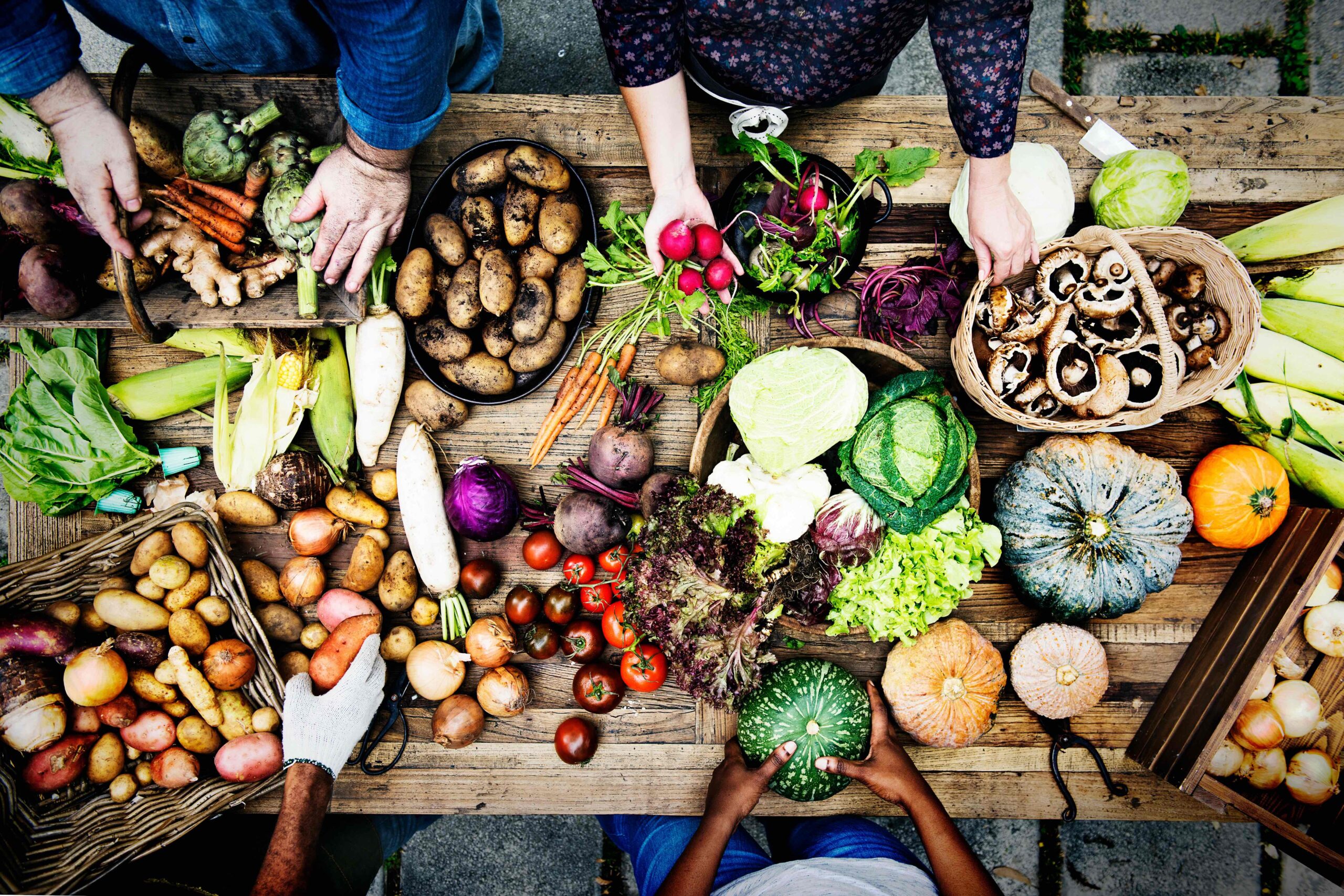 People collecting vegetables on a wooden table 