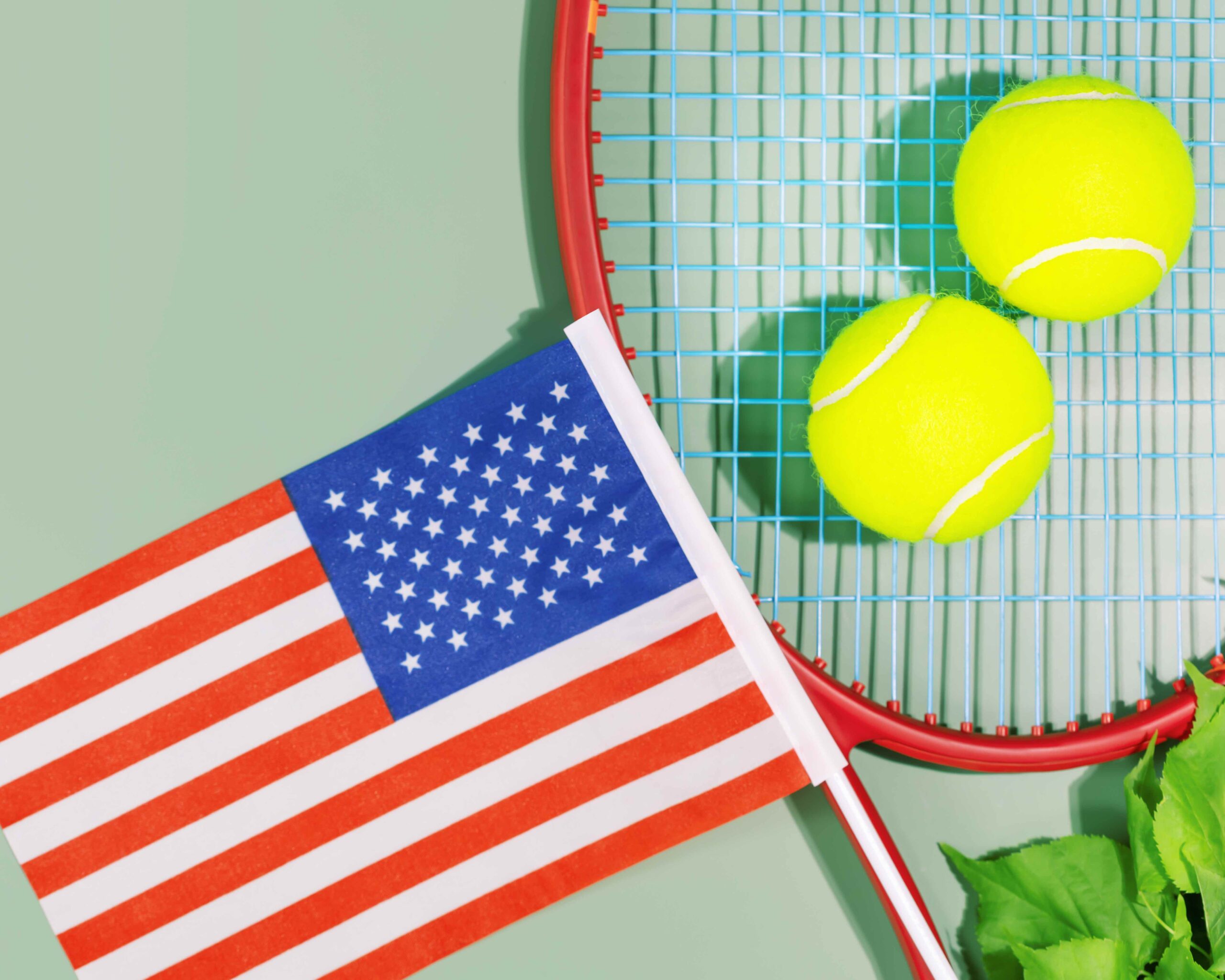 Tennis competition in the USA. Sport composition with yellow tennis balls, red racket and the flag of America on a green background. US open. Flat lay
