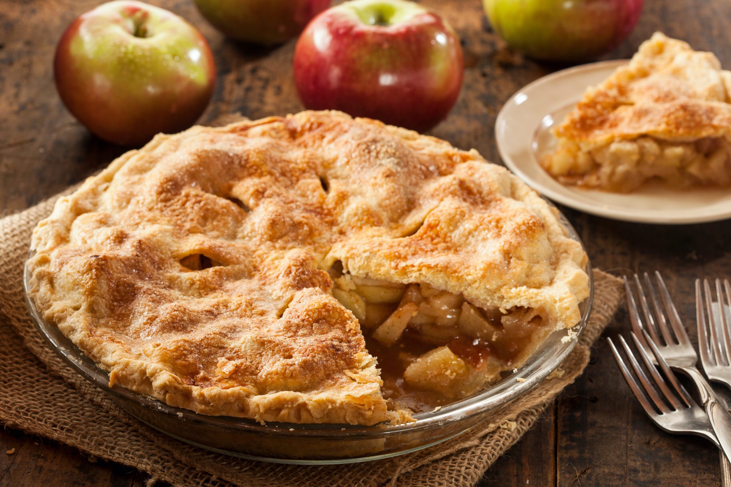 apple pie with one slice missing on wooden table 