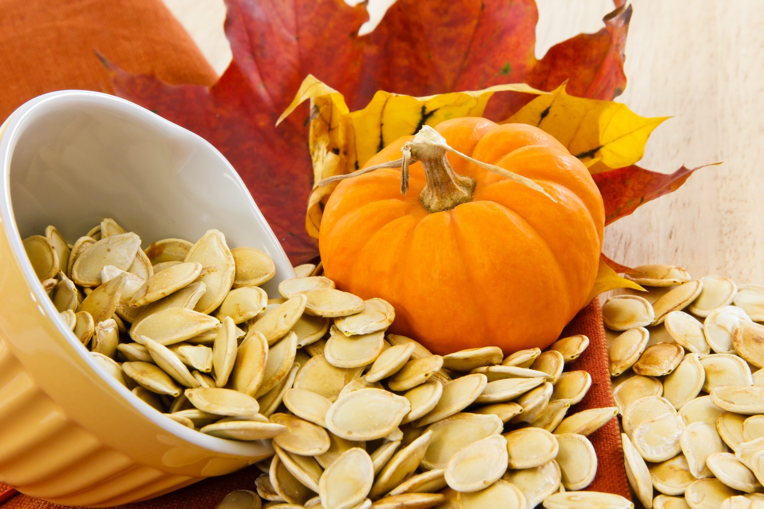 pumkin seeds spilling out of a little orange bowl