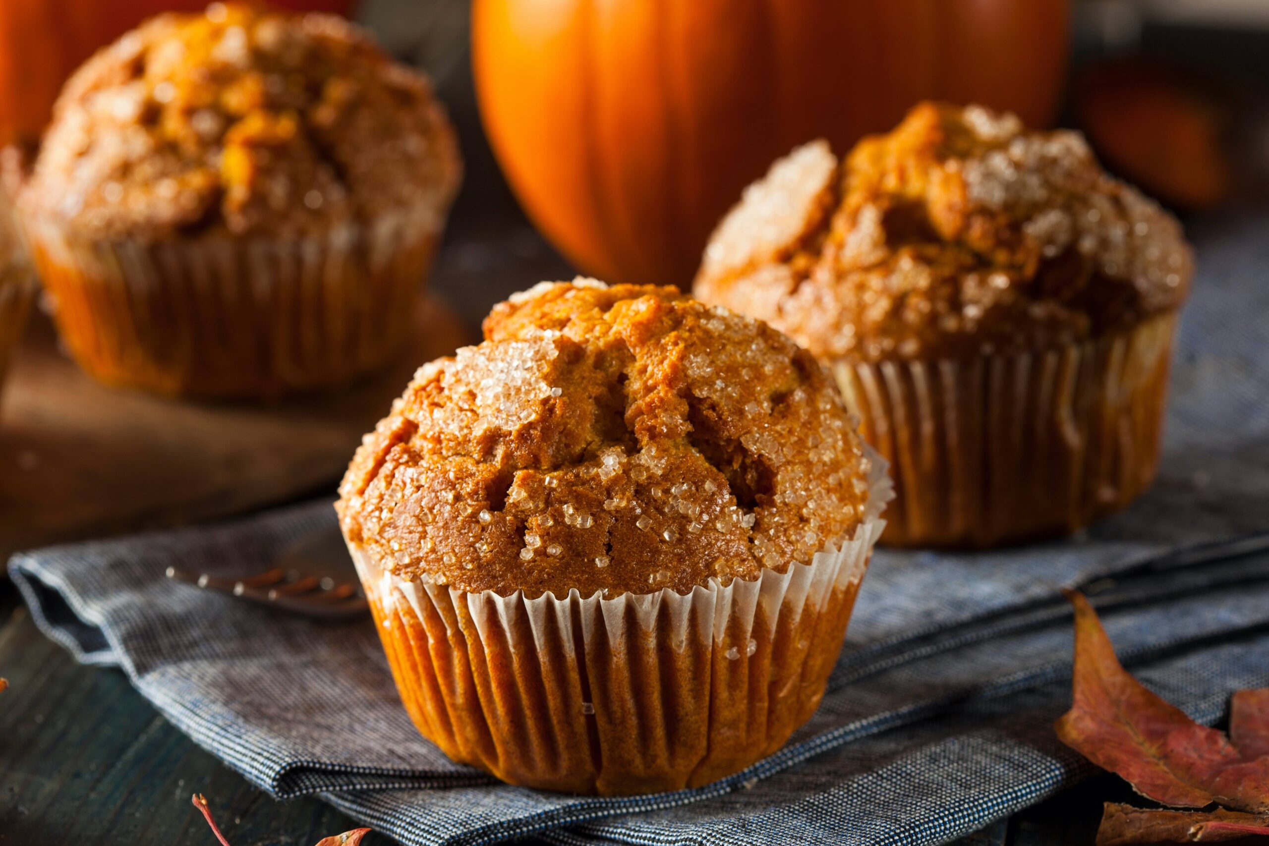 A close up of pumpkin muffins on a table with pumpkins
