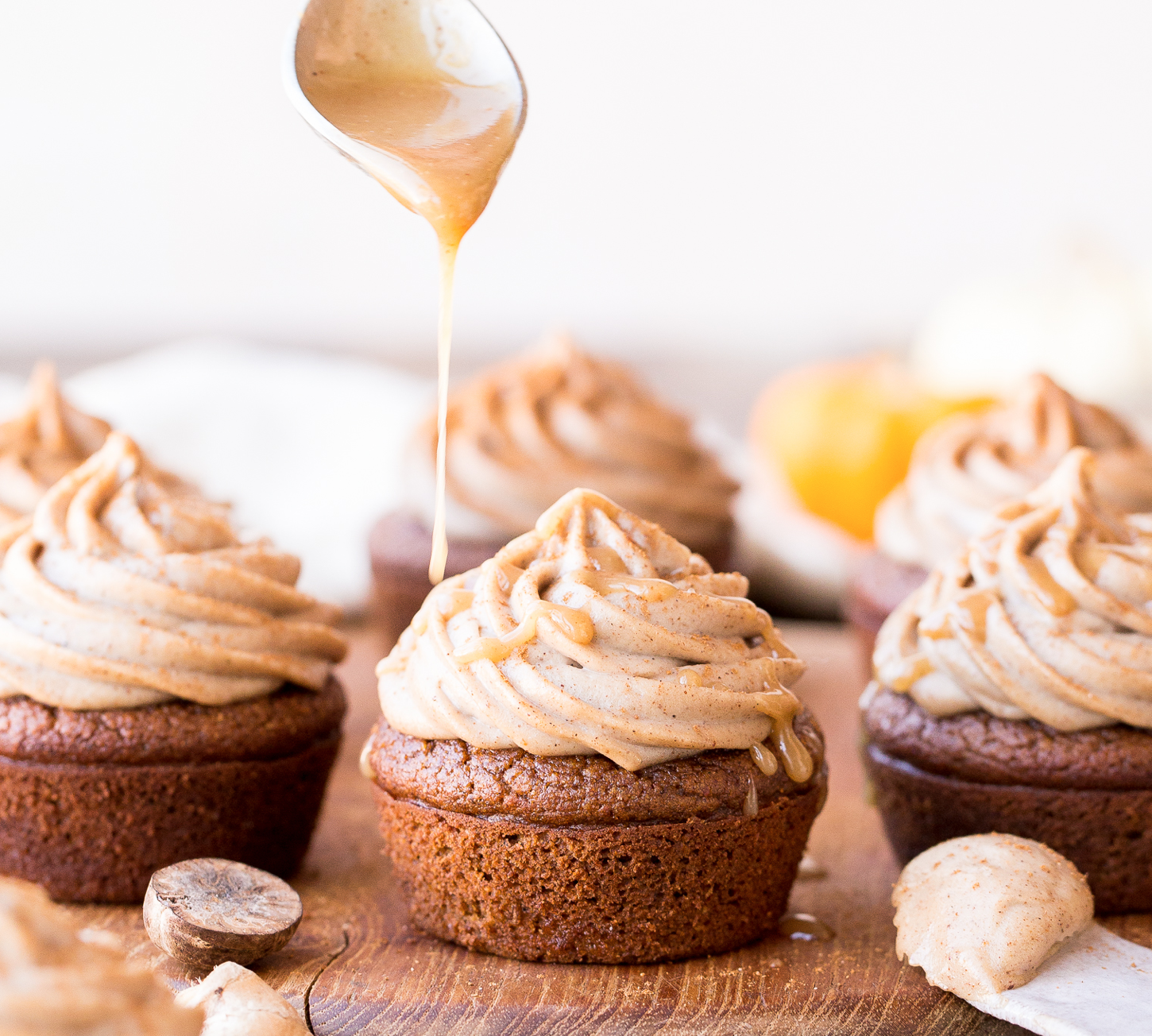 Close up of honey being drizzled on pumpkin chai cupcakes