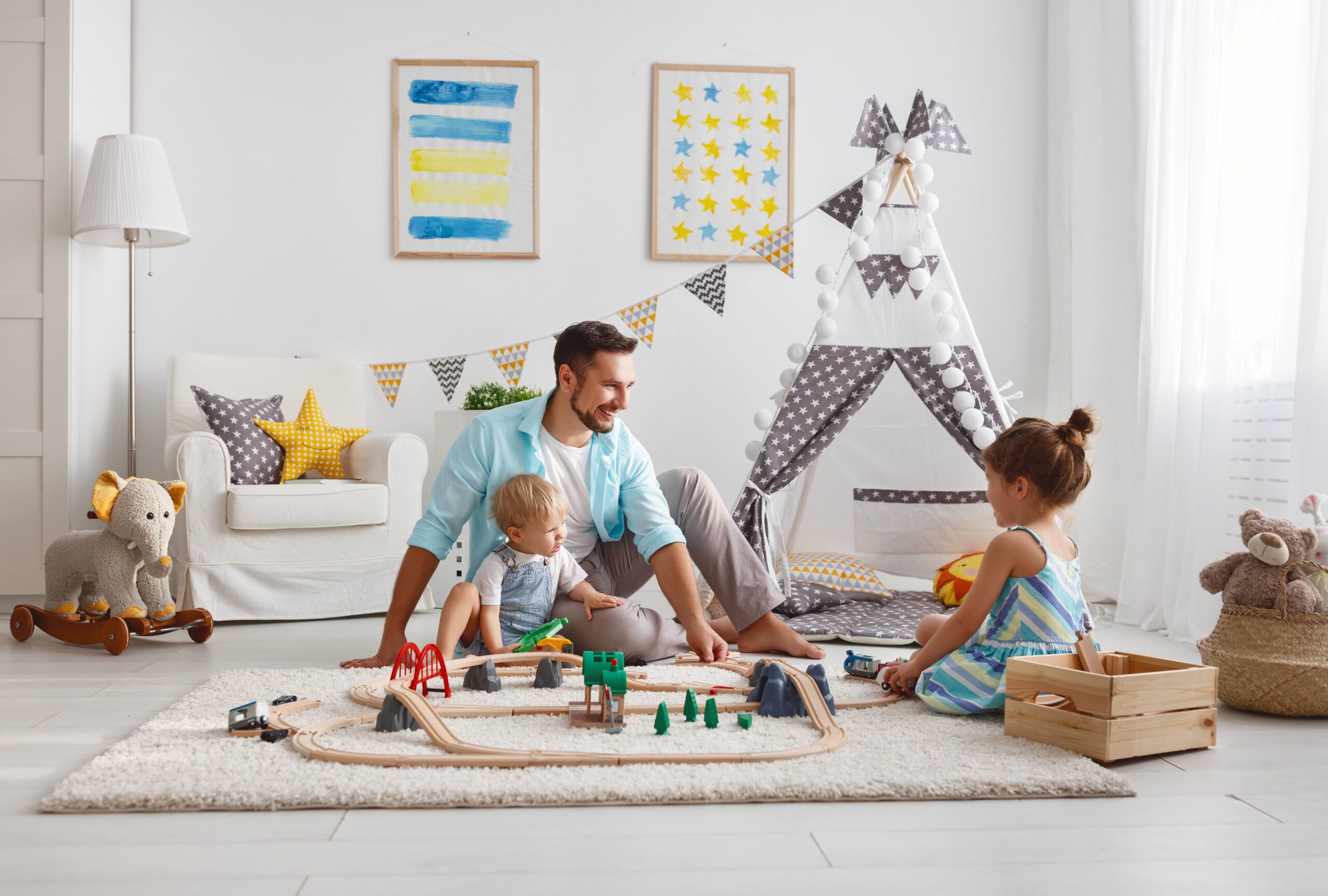 family father and children play a toy railway in the playroom