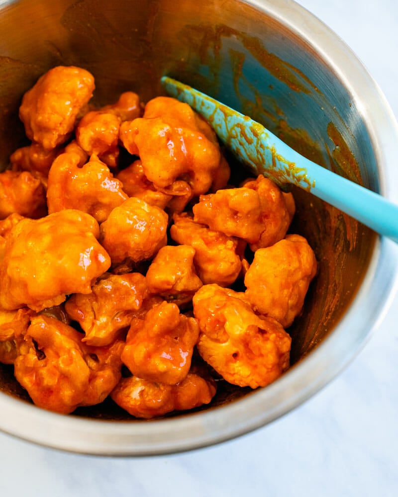 cauliflower bits in hot sauce in a mixing bowl