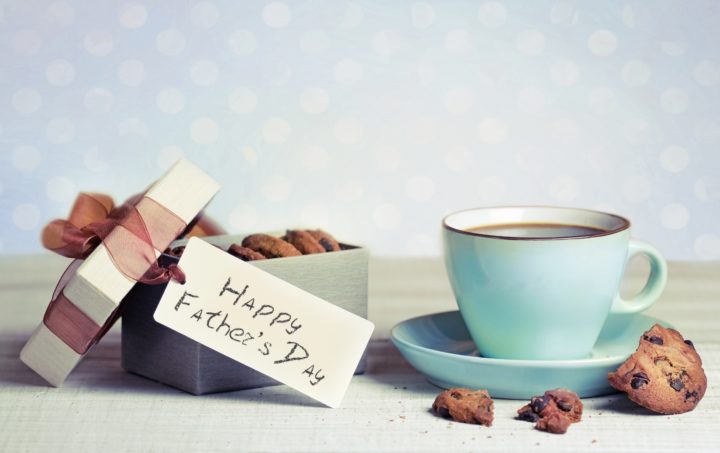 A box of cookies with a Happy Father's Day Tag and a coffee cup on a table 