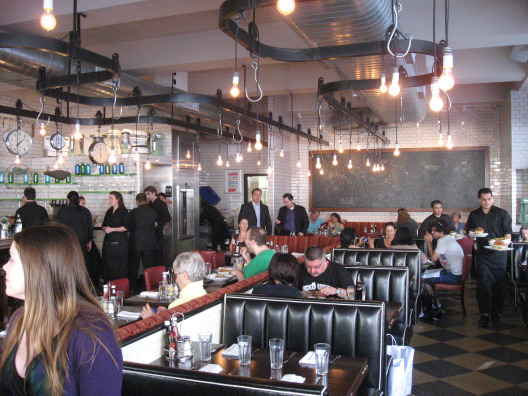 Five Napkin Burger in NYC interior filled with diner style seating, drop lights, and open style kitchen
