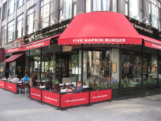 Five Napkin Burger in NYC exterior with bold red awning and outdoor seating