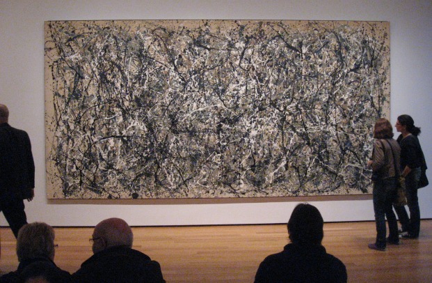 Viewers look on at a Abstract Expressionist painting of gray, black and white splatter paint - a Jackson Pollock original