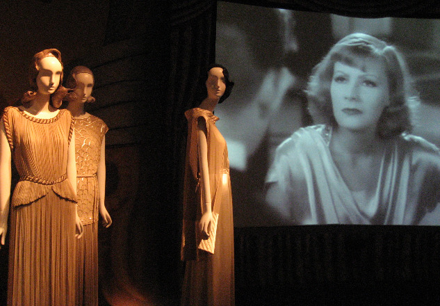 Fashion exhibition at the Met showcasing drapey, 1930s goddesses dresses and Greta Garbo on screen in the background.