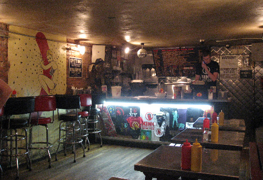 Crif Dogs NYC interior with bar tables and stools, brightly lit counter area, and low ceilings 