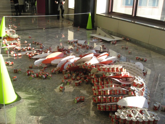 A Canstruction piece with orange cans that fell over - cans strewn all over the place