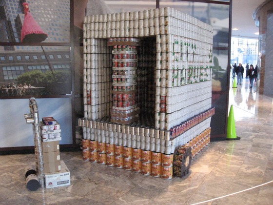 A truck with wheels set behind a hand truck all made from cans stacked together in the Canstruction NYC exhibition at the World Financial Center