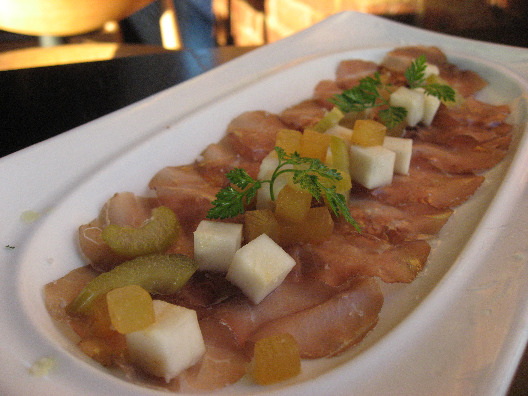 Thinly sliced ham with fresh fruit and garnish seved on an elongated white dish at Colicchio and Sons restaurant