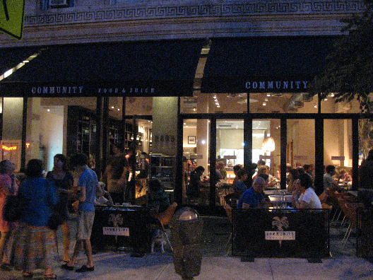 Community Food & Juice exterior with open windows, black awning and outdoor seating