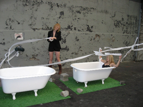Performance art piece at the Dumbo Arts Festival one woman in a bathtub on top of green astroturf and another woman holding a roll of toilet paper that is blowing in the wind