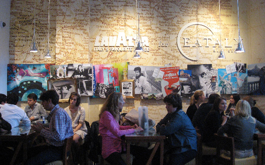 Mario Batali restaurant in New York interios filled with dinners at tables set in front of a wall size map of Italy