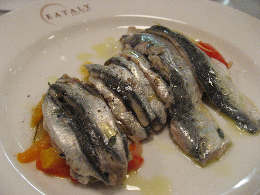 Sardines and anchovies over vinegary sweet peppers served on a white plate at Eataly NYC