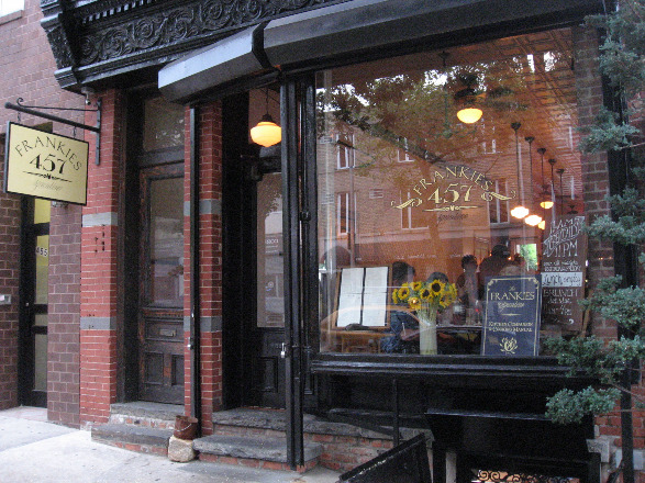 Frankies Spuntino restaurant exterior with wrought iron overhanging, open glass windows, and brick exterior