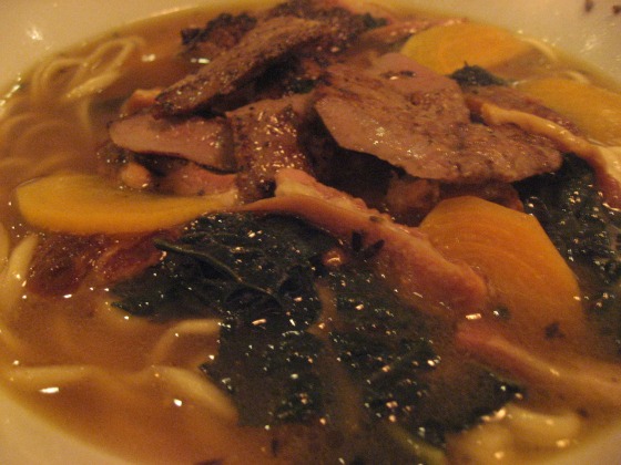 Smoked pork belly with brussels sprouts and kale on top of noodles served in a bowl at Hung Ry in New York City