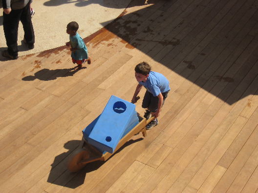 A child pushes a wheelbarrel full of blue foam building blocks at the Imagination Playground in New York City