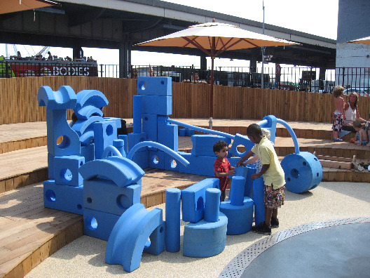 Blue foam building blocks allow kids to create structures and interact with other children at the Imagination Playground