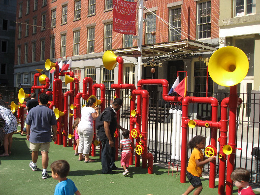 The Imagindation Playgrounds sound garden full of red piping materials with yellow horns to create various noises