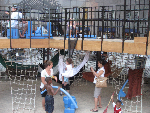 Families relax in the hammocks and children play on the rope ladders all hung from the Imagination Playground walkway