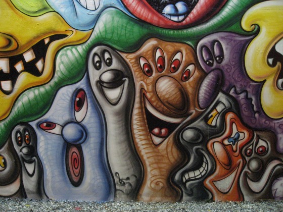 Close-up of grey, green, and brown cartoon faces on Houston Street wall mural by Kenny Scharf
