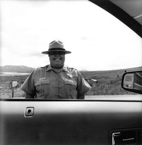 Lee Friedlander photograph of a police officer with a hat framed by the side window of a car