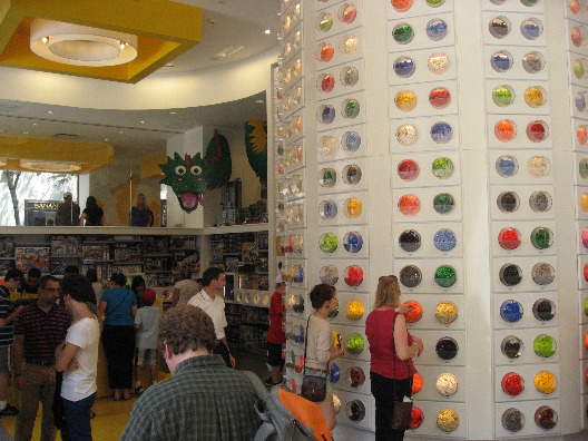 The Lego Store NYC full of people pulling legos out of bubbles on a curved wall full of legos of various shapes, sizes and colors.