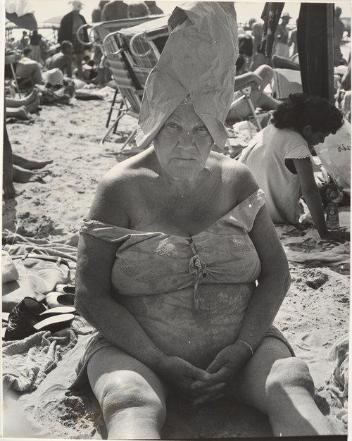 Leon Levinstein photographs on display at the MET of a heavy set woman on the beach with a paper bag on her head