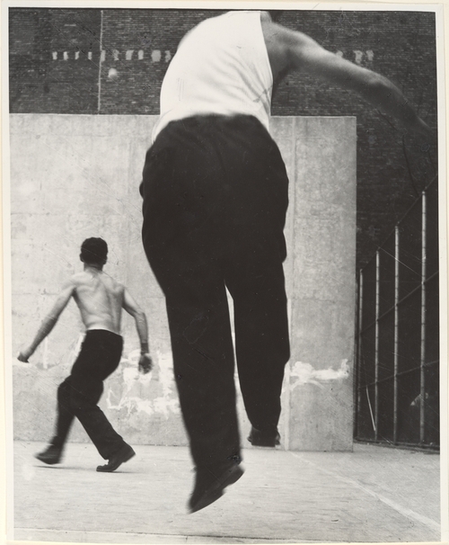 Leon Levinstein photograph of a man jumping in front and a man running in the background