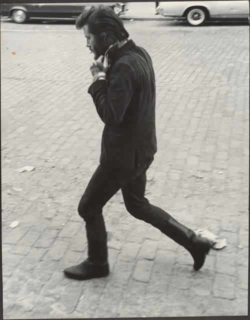 Leon Levinstein photograph of a man in the NYC streets walking fast and flipping his collar up