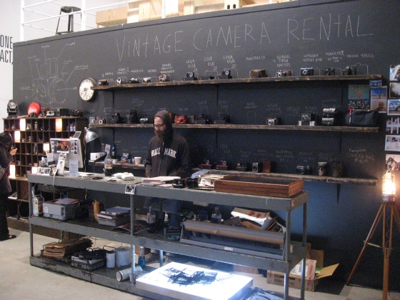 The camera borrowing station at the Levi's Photo Workshop a table and shelves filled with various cameras