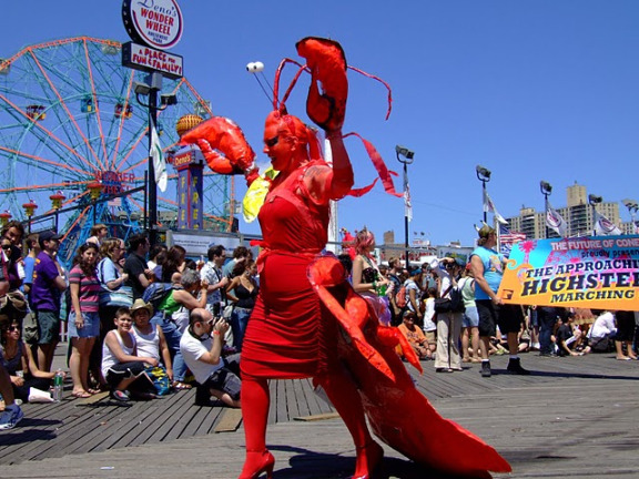 Coney Island Mermaid Parade picture of a marchers in a lobster costume with spectators and rides in the background