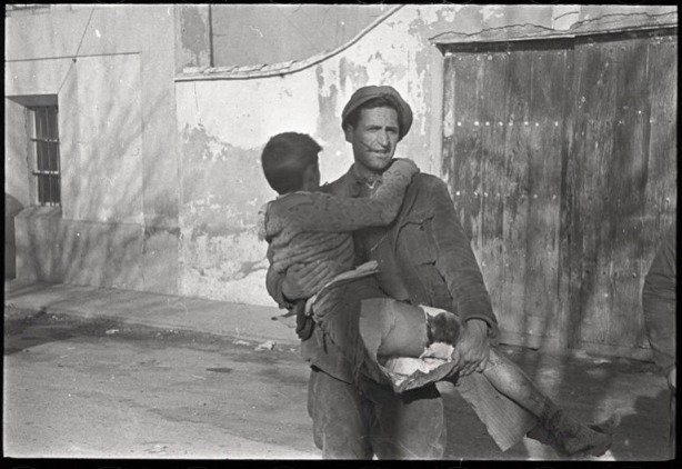Man holding a young boy with a leg wound fromt the Spanish Civil War on display at New Yorks International Center for Photography