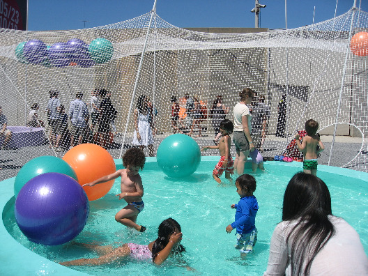 Solid Objectives Pole Dance poles, rubber balls and children playing in the pools of water