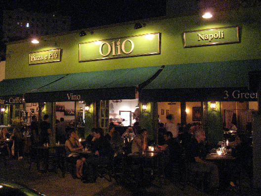 Olio Pizza NYC exterior with seating outdoors olive green painted building with dark green awnings