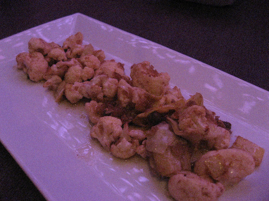 Elongated white plate with cauliflower sauteed and covered with a vinegarette sauce from Restaurant i