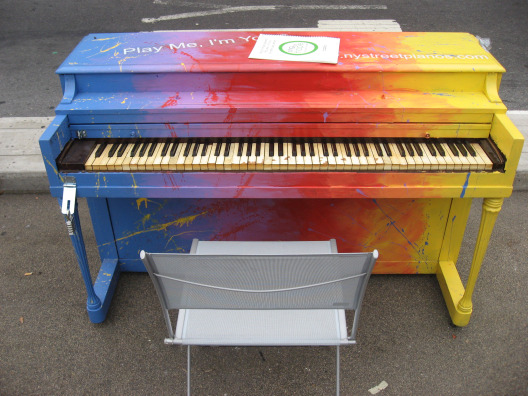 Luke Jerram Street Pianos NYC example of a blue, purple, red, orange and yellow painted piano on the street