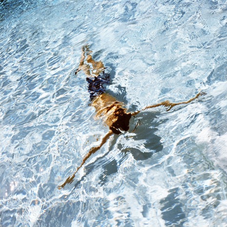 Male figure floating underneath the pool water at the Summer Places exhibition in NYC