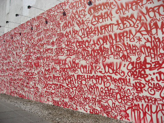 Close-up view of Twist and Amaze red spray paint tag pubilc art in NYC piece