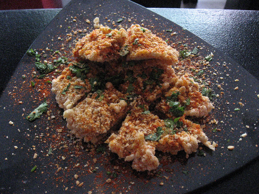 Tawainese restaurant Xiao Ye serves up peanut coated chicken on a black triangular plate sprinkled with red pepper and cilantro
