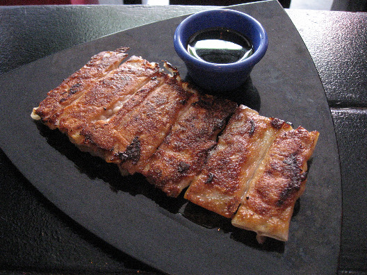 Xiao Ye potstickers on a triangular black plate with dipping sauce